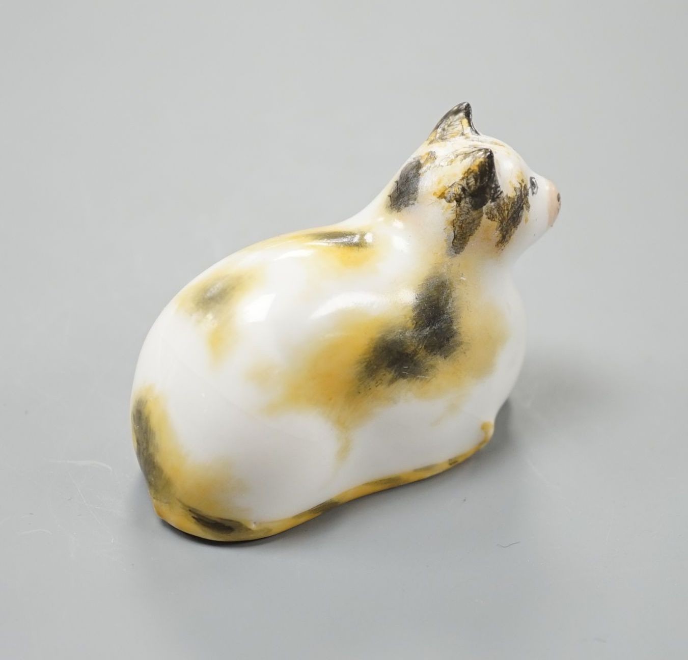 A rare Staffordshire porcelain figure of a recumbent cat, c.1835-50, with impossibly long tail, 6 cm long, Cf. Dennis G.Rice Cats in English porcelain, colour plate 54., Provenance: Dennis G.Rice collection